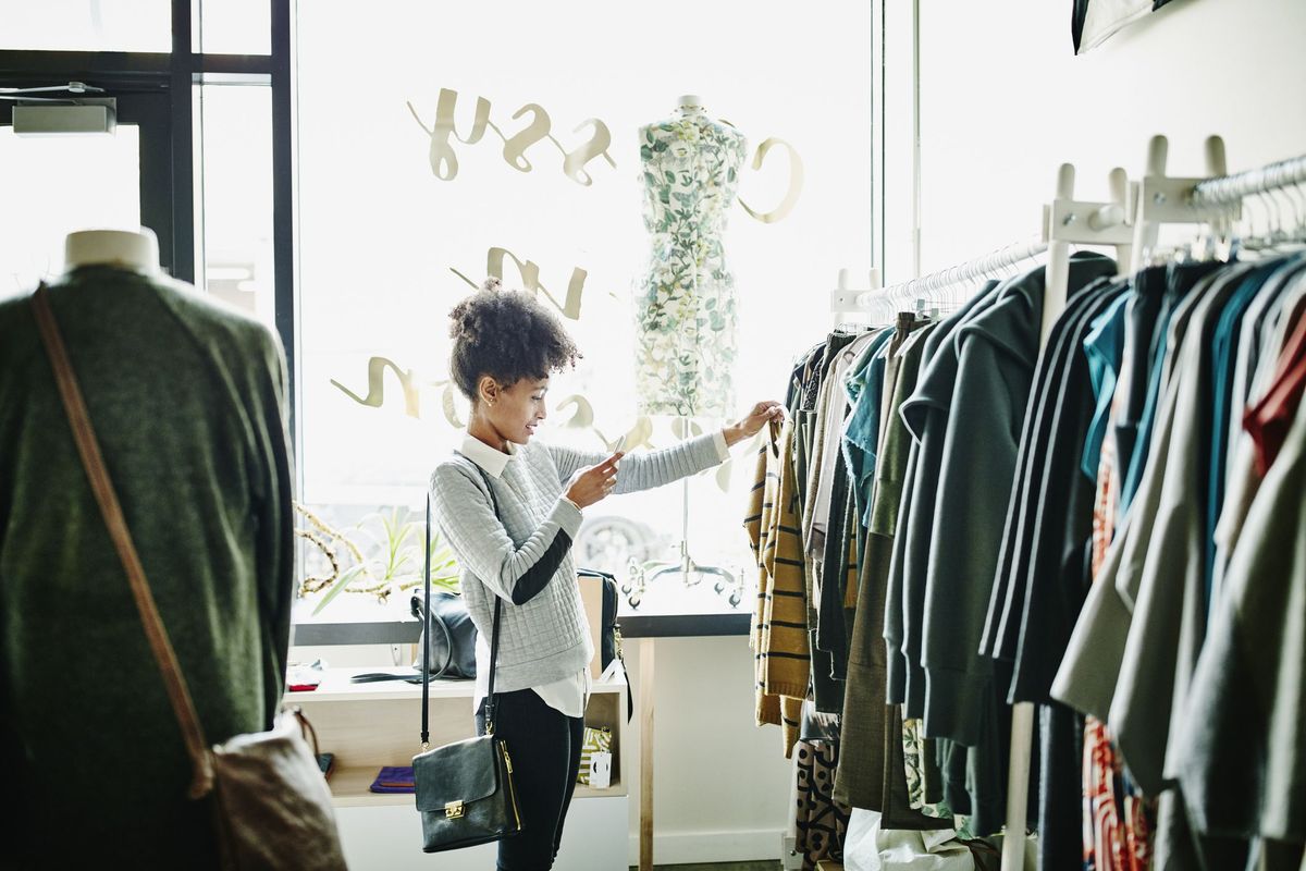 când încep vânzările din ianuarie, o femeie face fotografii de îmbrăcăminte cu smartphone în timp ce face cumpărături în magazinul de tip boutique