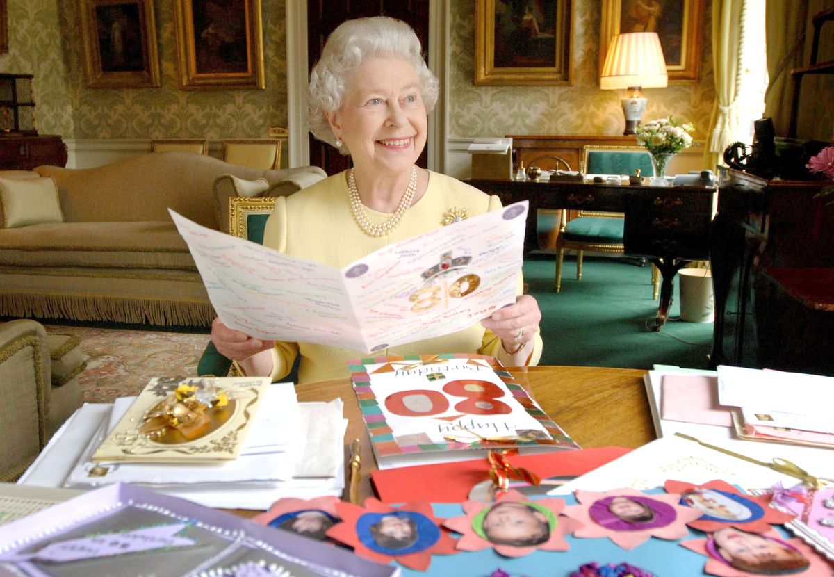 hm queen elizabeth ii sedi v regentni sobi v buckinghamski palači v Londonu, 20. aprila 2006, ko gleda nekaj kartic, ki ji jih je za njeno 80. rojstnodnevno fotografijo poslala zbirka anwar hussein rotawireimage